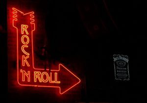 Immagine di un'insegna al neon rossa a forma di freccia, con la scritta "Rock and Roll" che brilla all'interno.